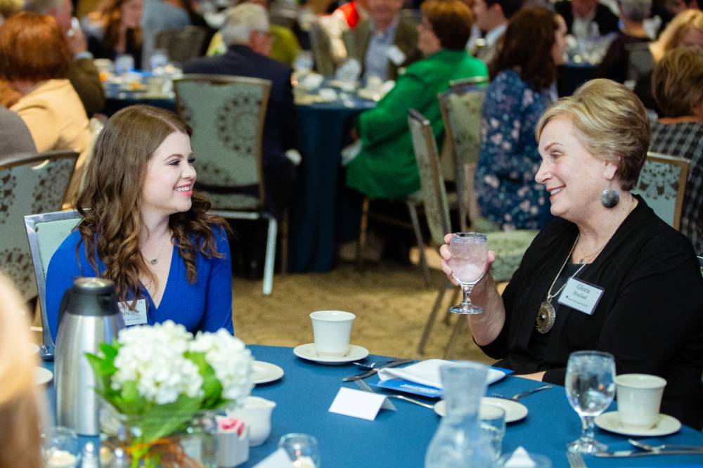 Two guests speaking to each other at a table at Scholarship Dinner 2019.